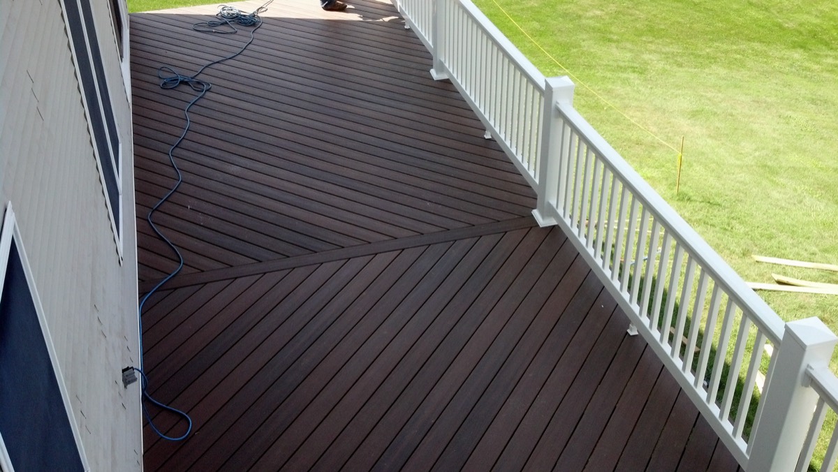 Deck after rebuild — dark Trex decking with white vinyl railing