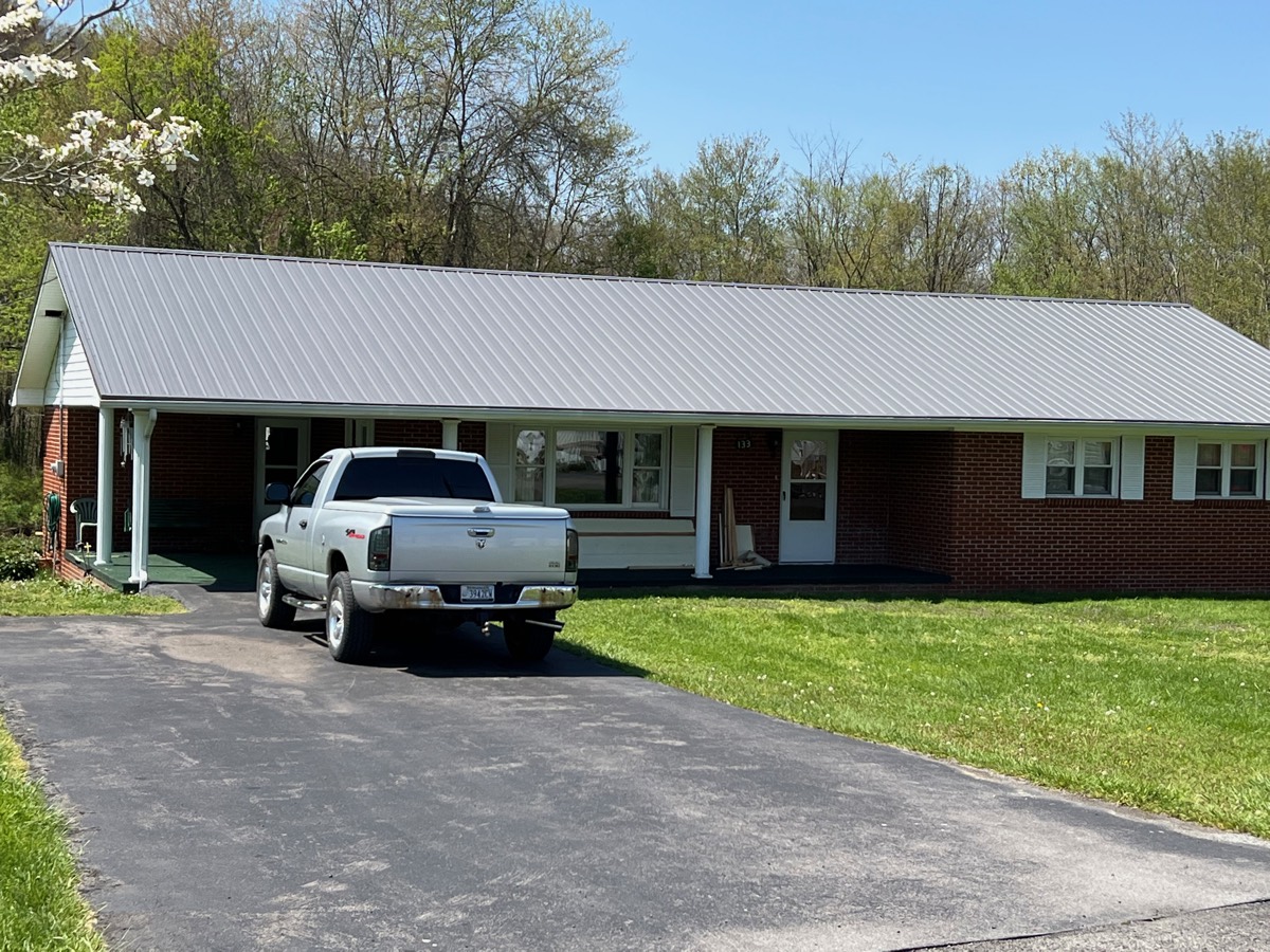 Roof after replacement — finished standing-seam metal roof on a brick ranch