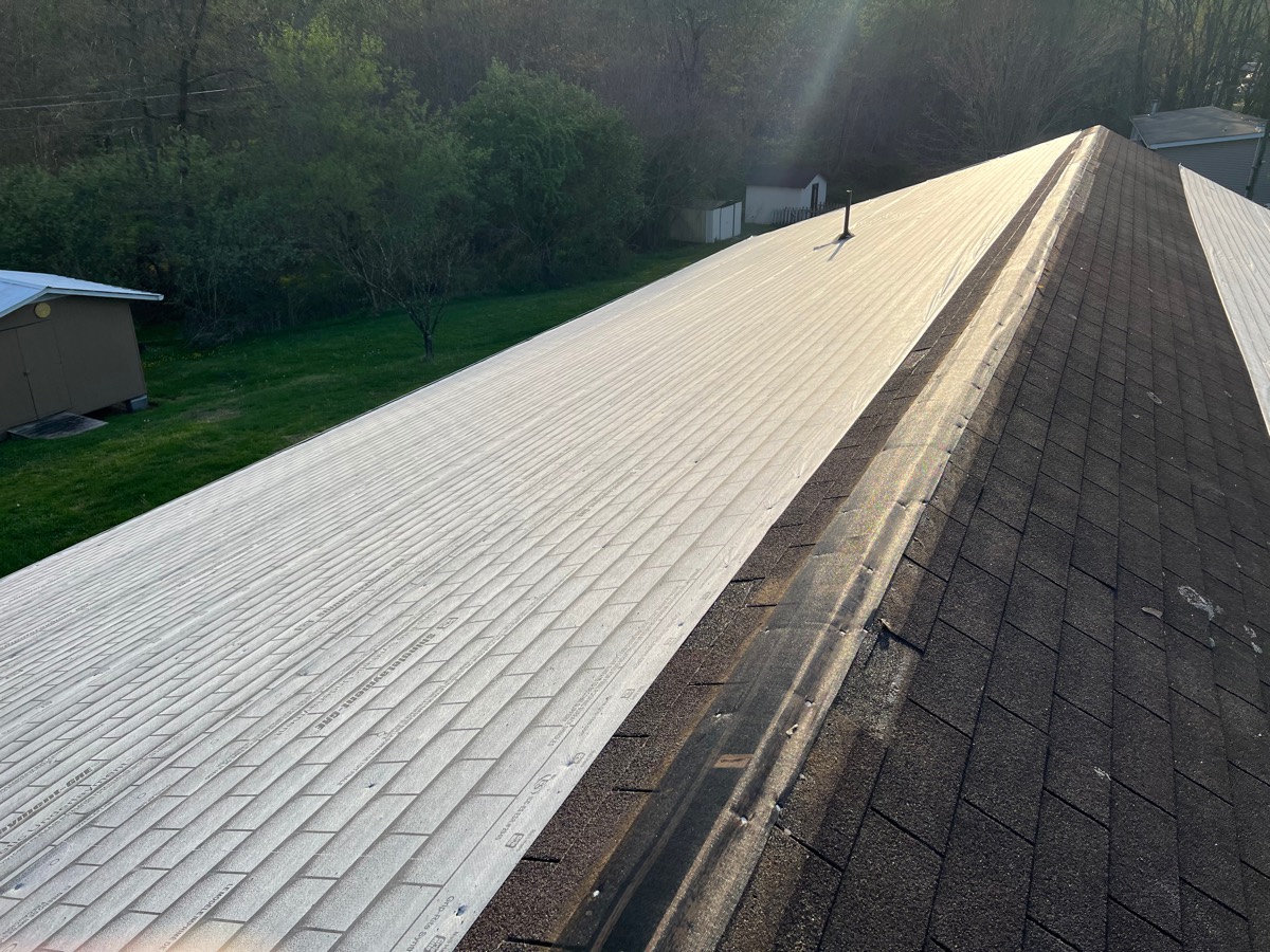 Roof before replacement — old shingles stripped beside new underlayment