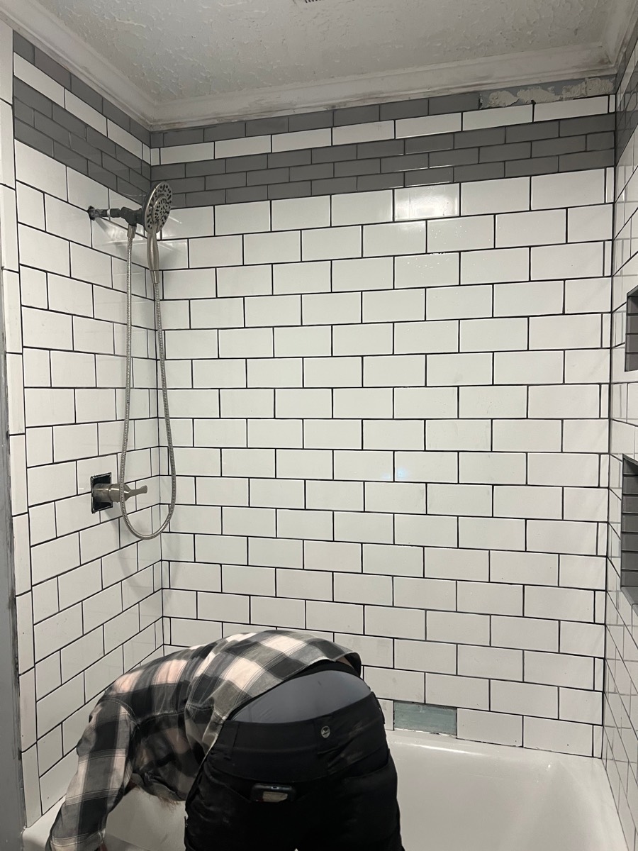 Tub surround after — white subway tile with gray accent band